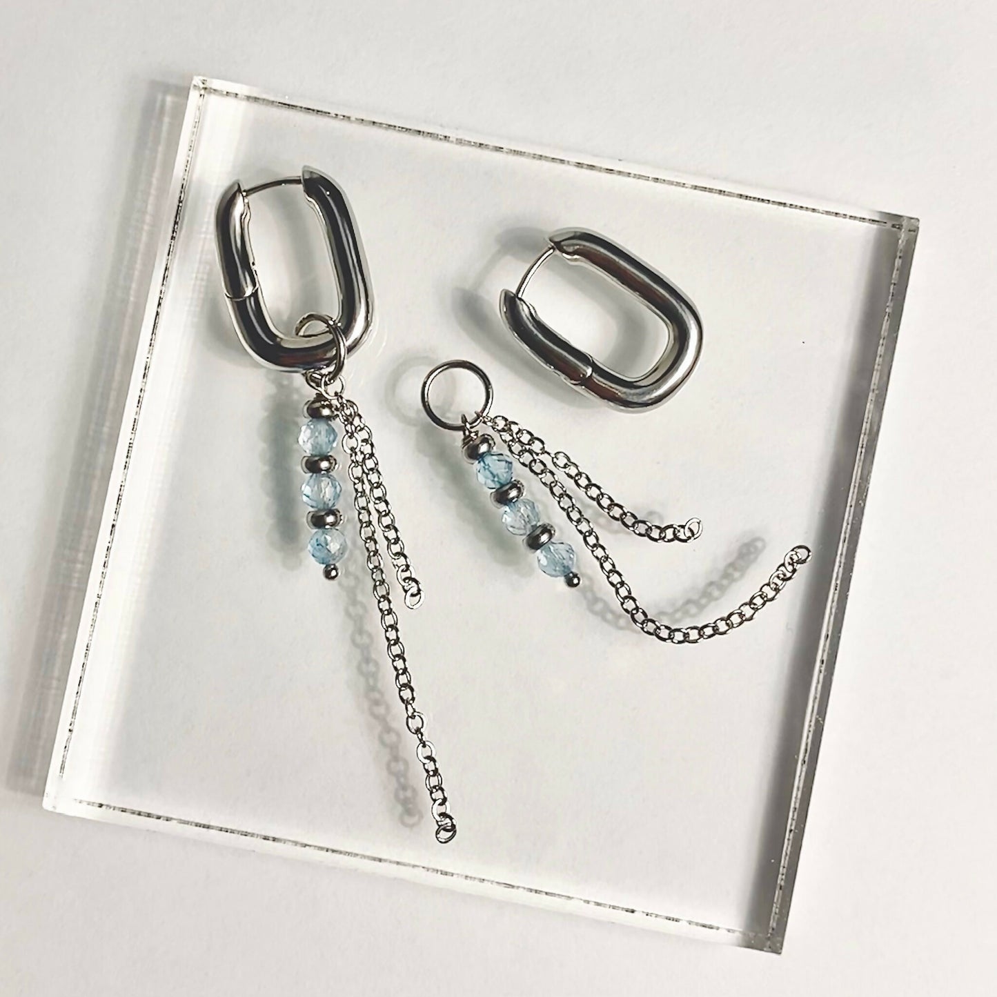 Hoop earrings with elegant dangle of blue topaz and chains in silver tone